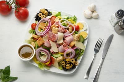 An antipasto salad with rolled deli meats, cheese, olives and egg