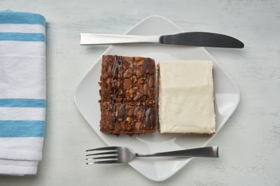 A specialty brownie beside a slice of plain cheesecake