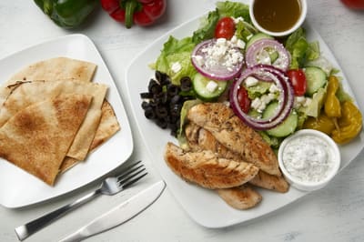 A chicken souvlaki salad with feta, olives and warm pita
