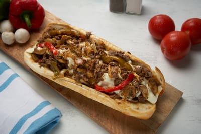 A steak hoagie with peppers, onions and melted cheese