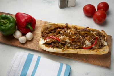 A steak hoagie on a wooden board, seen along its length