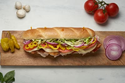 A turkey bacon sub with lettuce, tomato, banana peppers and red onion