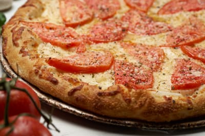 A white pizza with sliced tomato, shot from above